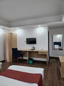 Habitación de hotel con cama, escritorio y TV. en Shanol Residency en Gangtok