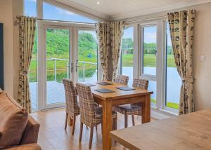 a dining room with a table and chairs and a large window at Lakeside Luxury Lodges in Thorney