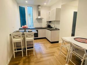 a kitchen with white cabinets and a table and chairs at Nuovissimo trilocale in centro : Ca’ Del Mar in Sanremo