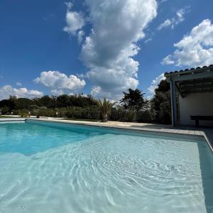 une grande piscine bleue avec un ciel nuageux dans l'établissement Le 36 Maison d'hôtes Piscine & Spa, à La Flotte