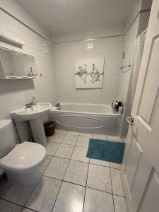 a bathroom with a toilet and a tub and a sink at Coleraine Riverside apartment in Coleraine