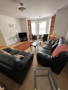 una sala de estar con 2 sofás de cuero negro y una mesa. en Coleraine Riverside apartment en Coleraine