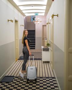 a woman pulling a suitcase down a hallway at Neptun Badacsony in Badacsonytomaj