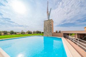 uma piscina com um moinho de vento em cima de uma casa em Sa Tanca em Se Casa Blanca