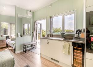 eine Küche mit grünen Wänden und Fenstern sowie einem Waschbecken in der Unterkunft Calvesland Hideaway in Manorbier