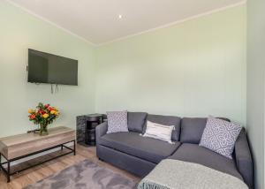 uma sala de estar com um sofá azul e uma televisão em Calvesland Hideaway em Manorbier