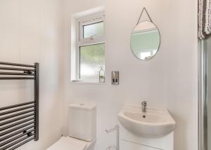 La salle de bains blanche est pourvue d'un lavabo et d'un miroir. dans l'établissement Calvesland Hideaway, à Manorbier