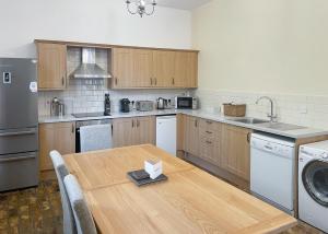 a kitchen with a wooden table and a kitchen with a dishwasher at Haveringland Hall in Cawston