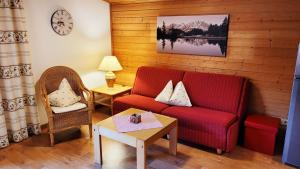 ヴェステンドルフにあるApartment Neuhaushofのリビングルーム(赤いソファ、テーブル付)