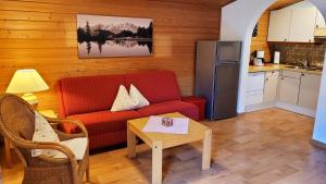 Apartment Neuhaushof في وستندورف: غرفة معيشة مع أريكة حمراء وطاولة