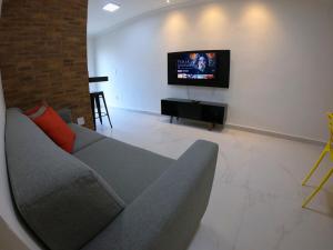 Una sala de estar con un sofá y un televisor de pantalla plana. en TH Flats GV Shopping II, en Governador Valadares