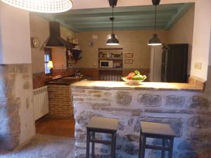 a kitchen with a stone counter and two stools at Casa Cuqui in Orgaz