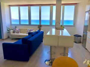 a living room with a blue couch and a table at Vistas Mar Playa Las Canteras primera línea Wifi in Las Palmas de Gran Canaria