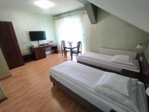 a bedroom with two beds and a table and a chair at Restauracja Kargul noclegi in Łęczyca +16 photos