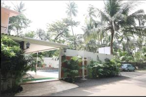 a house with a porch and a fence and palm trees at SAVI 4BHK VILLA ALIBAUG in Alibaug