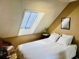 Un dormitorio con una gran cama blanca con ventana. en Central 2BR with balconies and art in historical university area, en Bergen