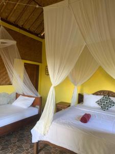a bedroom with two beds with mosquito nets at Jana's Homestay in Sidemen