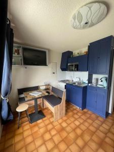 eine Küche mit blauen Schränken, einem Tisch und einem Siddx sidx sidx in der Unterkunft Studio Myrtilles du Léman vue sur lac et montagne in Thollon