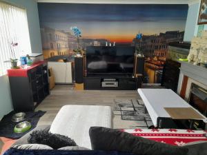 uma sala de estar com uma televisão de ecrã grande e um sofá em Cichy I uroczy pokój em Newtongrange