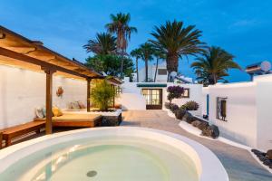 einen Pool im Hinterhof eines Hauses mit Palmen in der Unterkunft Villa Munay in Puerto del Carmen