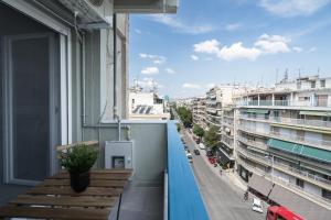 einen Balkon mit einer Holzbank und einer Stadtstraße in der Unterkunft Feidias Apartment - 1 bedroom in Thessaloniki