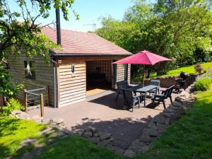 un patio con mesa, sillas y sombrilla en Tanners Lodge, en Bewdley