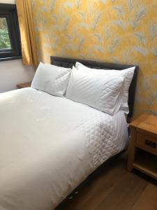 Una cama con sábanas blancas y almohadas en un dormitorio en Tanners Lodge, en Bewdley