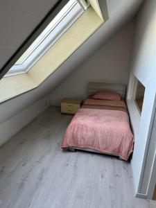 1 dormitorio en el ático con cama y ventana en Duivenboshuisje, en Herzele