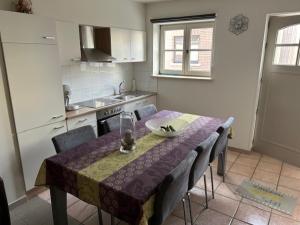 een keuken met een tafel met een paars tafelkleed bij Duivenboshuisje in Herzele