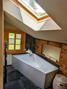 a large white bath tub in a bathroom with a skylight at Chalet Grittelihus, large bathroom, Lots of living space, nahe Interlaken in Diemtigen