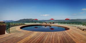 a swimming pool on a wooden deck with red umbrellas at Hotel Carre Noir in Porto-Vecchio