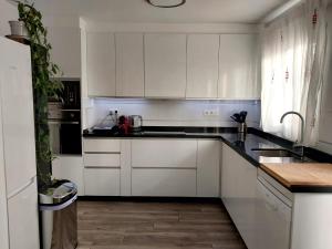 una cocina blanca con armarios blancos y fregadero en Málaga casa grande familiar en Málaga