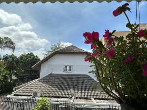 een wit huis met een dak met roze bloemen bij An‘s Home in Chiang Mai