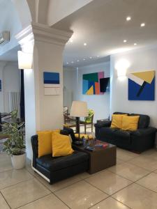 a living room with two black couches and yellow pillows at Hotel Venezia in La Spezia