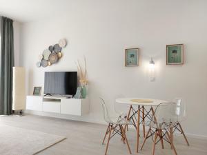 een witte woonkamer met een tafel en een tv bij Linden Apartman 104 - Adults Only in Mosonmagyaróvár