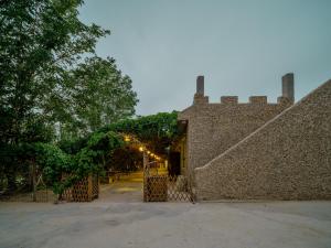 a building with a wall with a gate and trees at Dunhuang Hu Yang Inn in Dunhuang