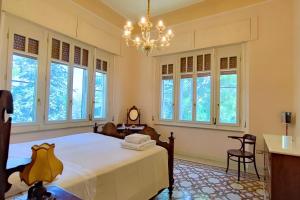 1 dormitorio con 1 cama, lámpara de araña y ventanas en Villa Fazi - Liberty Style Villa With Private Pool & Park, en Ortezzano