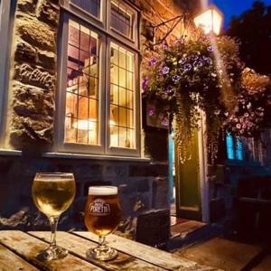 dos copas de vino sentadas en una mesa frente a un edificio en Burnley country house en Hutton le Hole