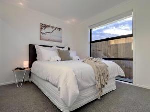 um quarto branco com uma cama grande e uma janela em Villa in Central Hamilton - By KOSH BNB em Hamilton