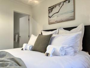 um quarto com uma cama branca e almofadas brancas em Villa in Central Hamilton - By KOSH BNB em Hamilton