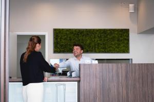 a man and a woman shaking hands at a counter at Hotel Richmond in Blankenberge