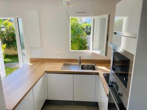 Una cocina con gabinetes blancos y un fregadero y una ventana. en Villa Bella à 250m des plages, en Biarritz