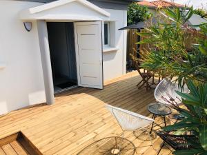 Un patio con sillas y mesas en una terraza de madera. en Villa Bella à 250m des plages, en Biarritz 2 fotos más
