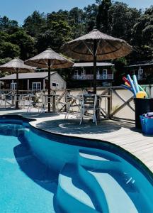 a swimming pool with chairs and umbrellas on a deck at Anchor Lodge Motel in Coromandel Town