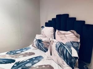 Cama con sábanas y almohadas azules y blancas en Husein Accommodations en Ciudad del Cabo