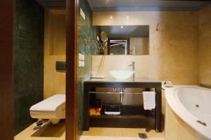 y baño con bañera, lavamanos y bañera. en Civitas Suites Hotel, en Rethymno