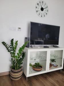 a white cabinet with a tv and a clock on the wall at Apartament Pod Orzechem in Bydgoszcz