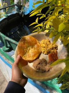 una persona sosteniendo un plato con una dona en él en Neer Stays en Munsyari