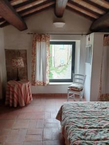 una camera con letto, finestra e sedia di Alloggio turistico Il Villino in Maremma a Farnese