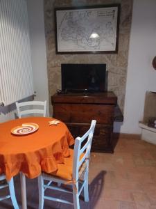 una sala da pranzo con tavolo, sedie e TV di Alloggio turistico Il Villino in Maremma a Farnese